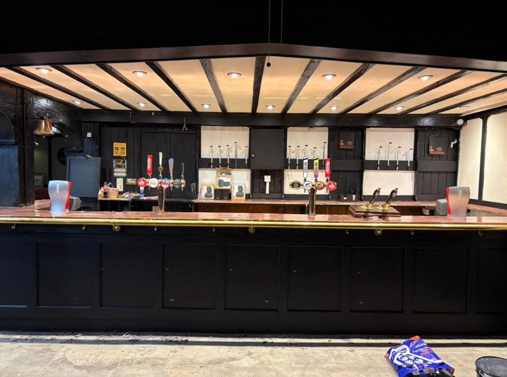 The long main bar at The Rock and Heifer, showing hand pumps, copper bar top, brass rail and beamed canopy