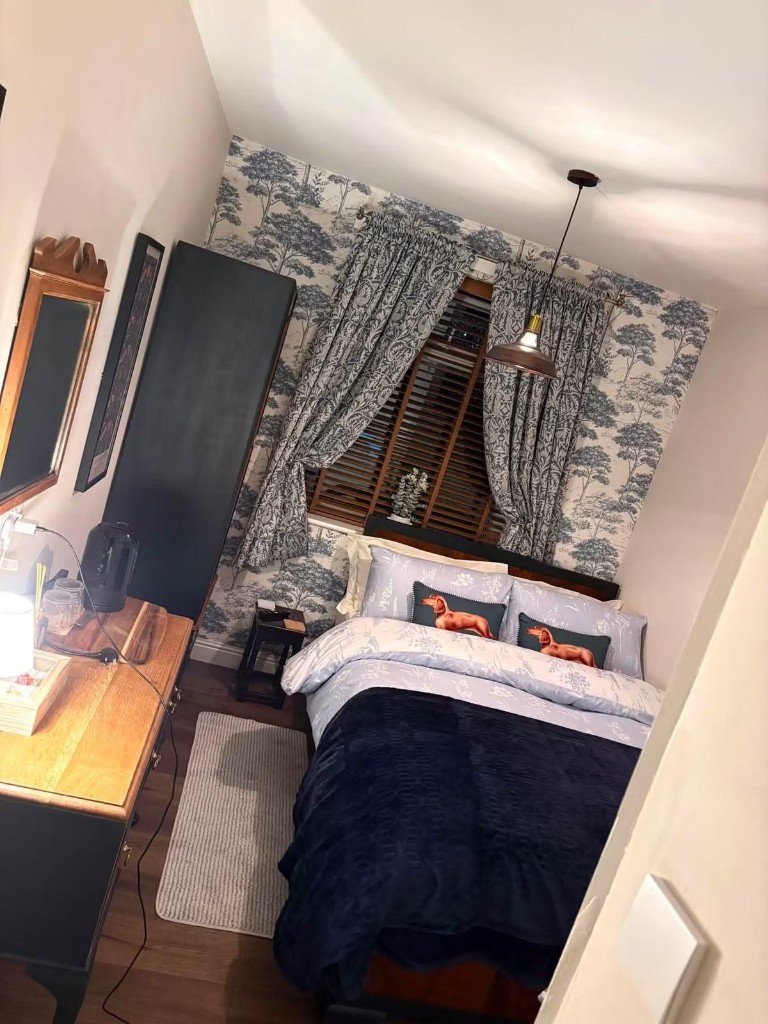 The Woodland Room: a guest bedroom with blue tree-print wallpaper and sausage-dog cushions