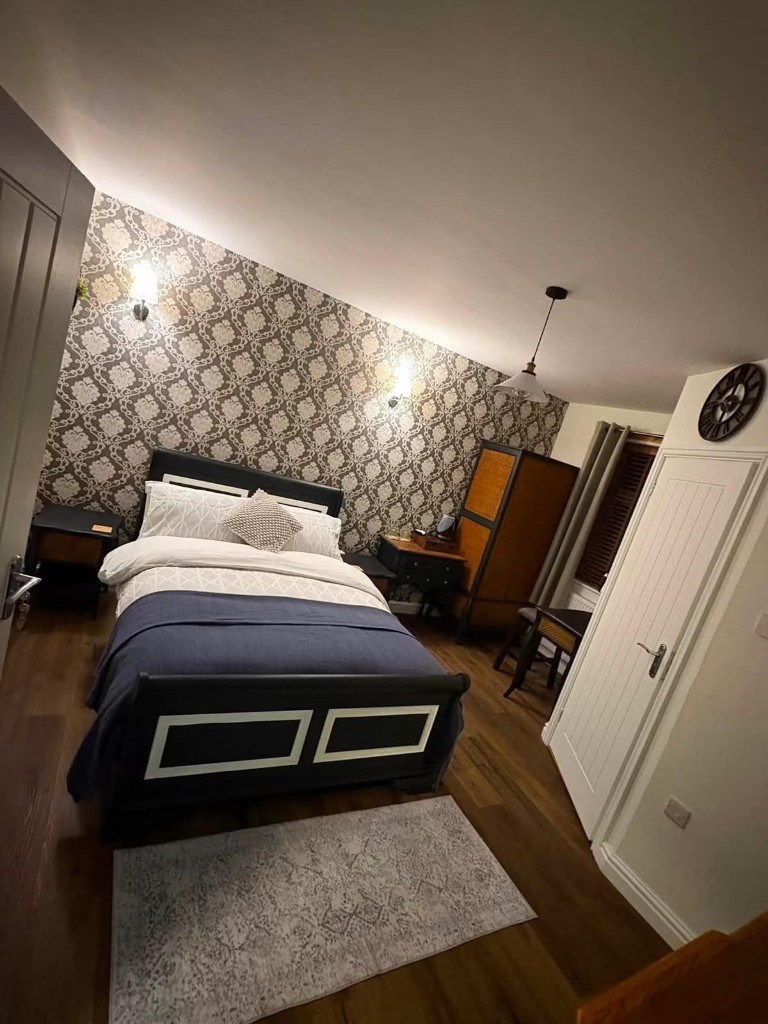 The Damask Room: a guest bedroom with a damask feature wall, sleigh bed and warm wall lighting